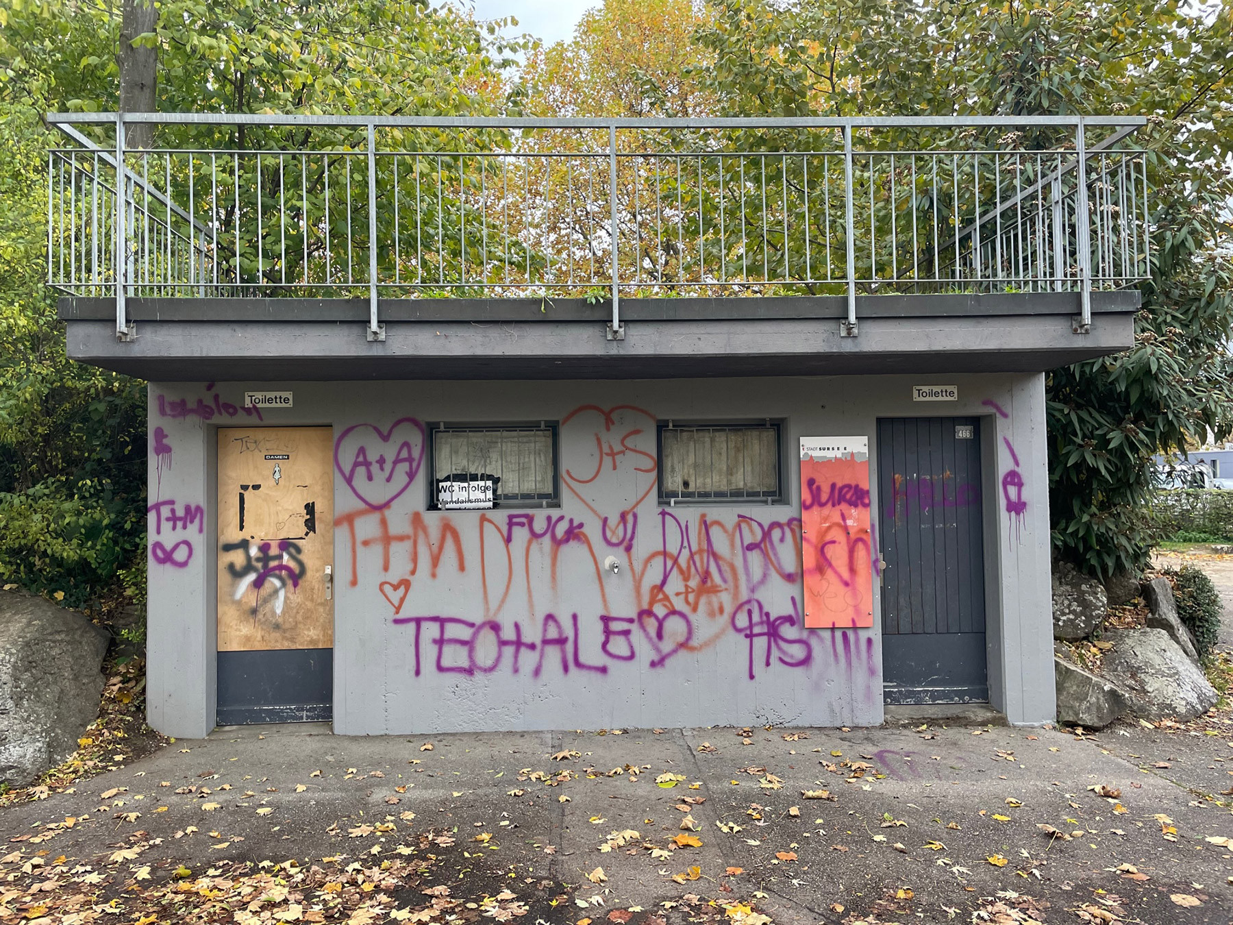 Öffentliches WC-Gebäude im Kyburg Park Sursee vor der Umnutzung durch kunzarchitekten. Graue Betonfassade mit Graffiti und verschlossenen Türen – später zur sommerlichen Parkbuvette umgebaut.