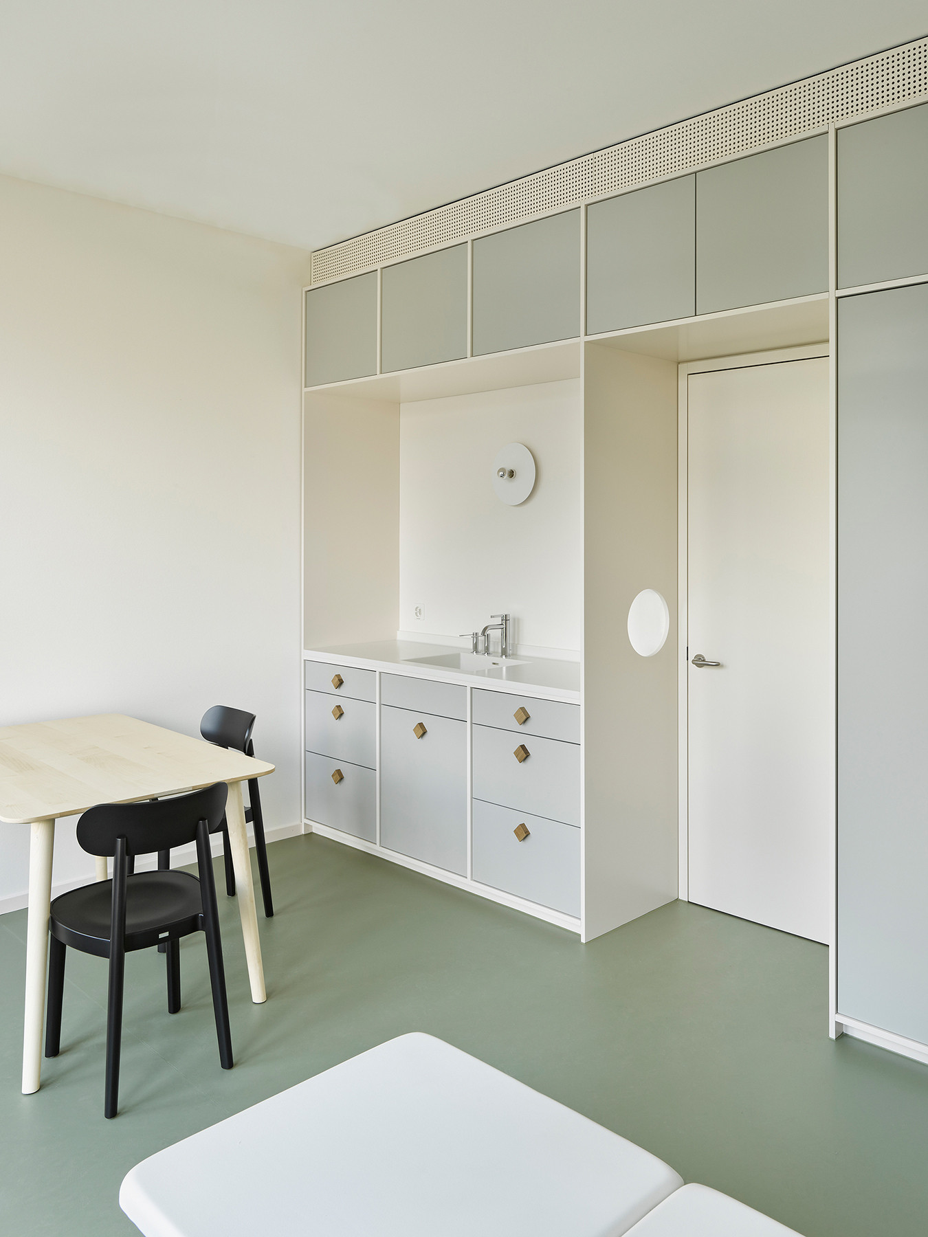 Harmonisch gestaltetes Patientenzimmer mit feinen Farbnuancen. Linoleum am Boden und sorgfältige Schreinerarbeiten bieten viel Stauraum.