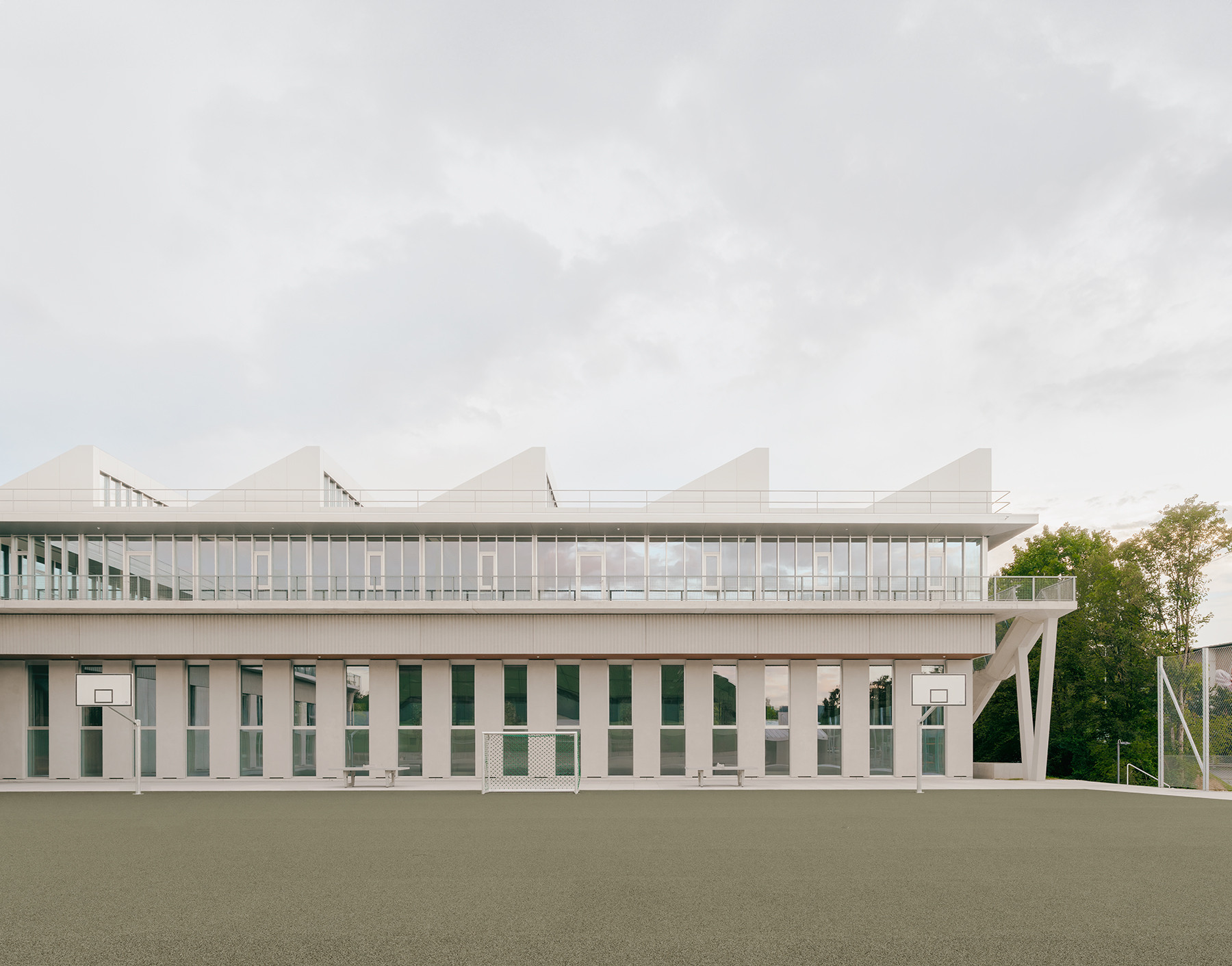 Fassadenansicht des Schulhauses Zirkusplatz mit markanten Oberlichtern und strukturiertem Baukörper.