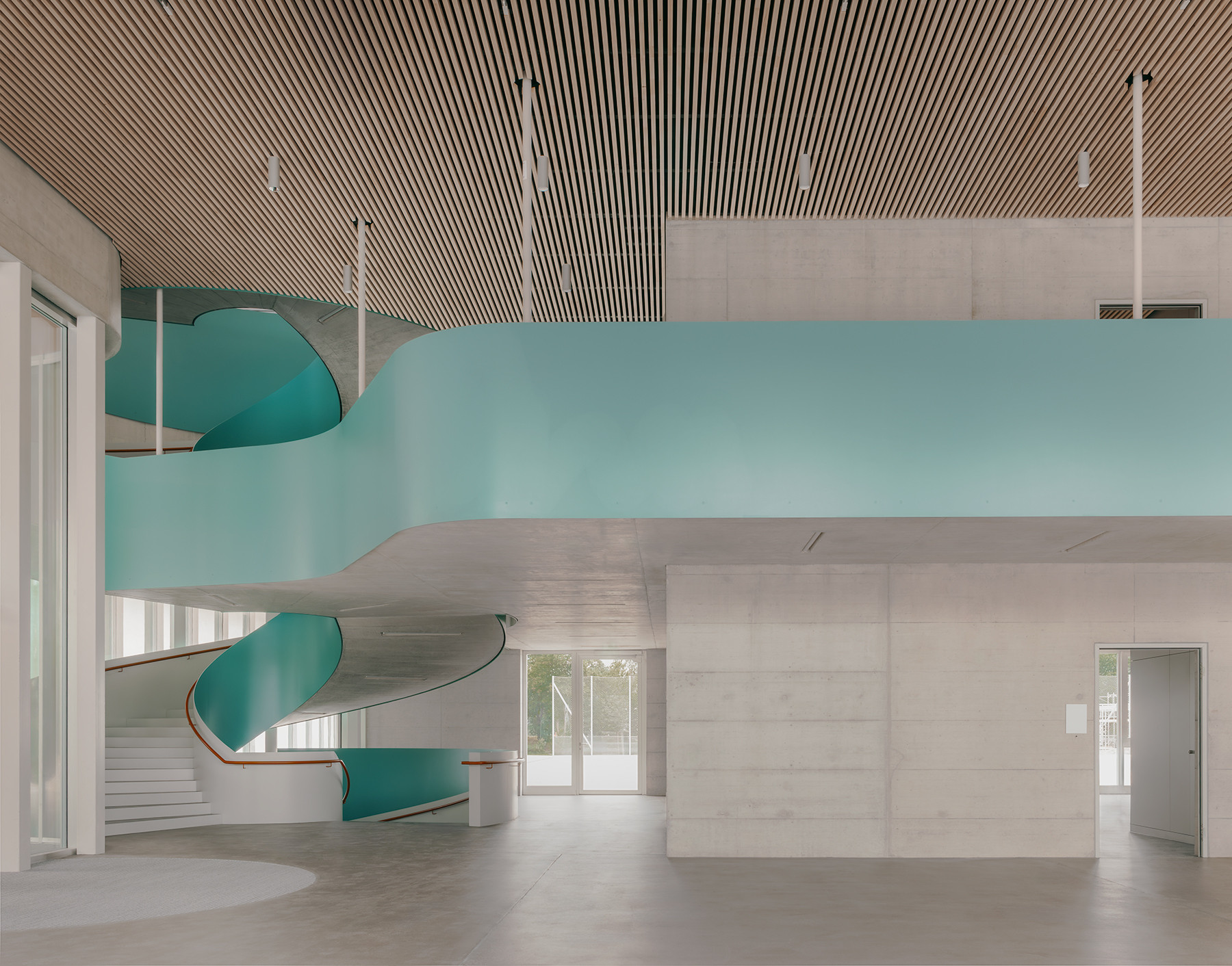 Ansicht der grosszügigen Wendeltreppe im Innern des Sekundarschulhauses Zirkusplatz, mit Sichtbezug zur Sporthalle.