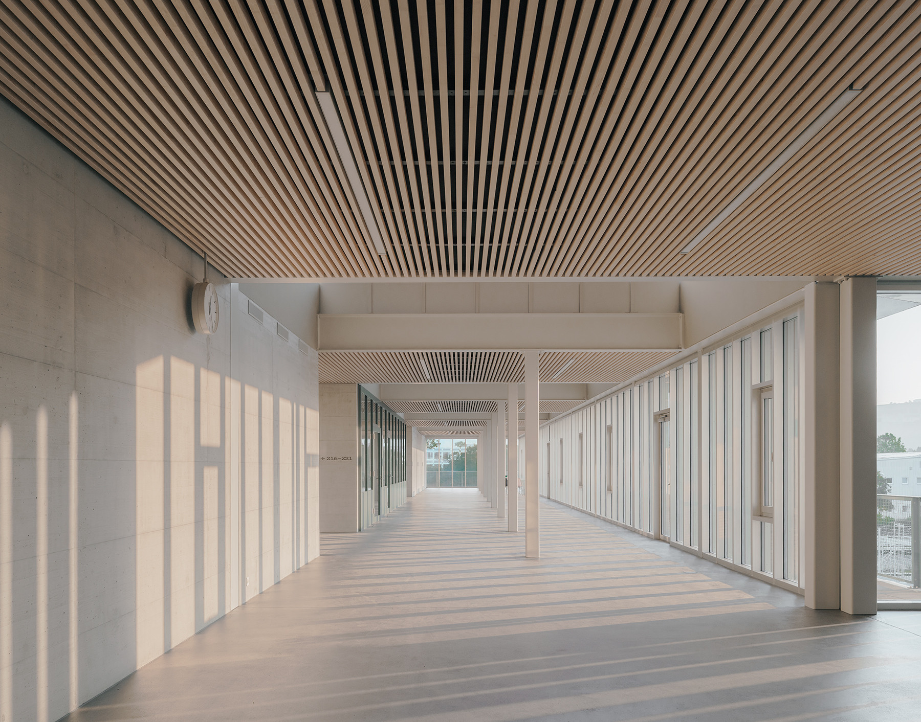 Blick in einen offenen Schulflur mit Holzverkleidung und Tageslicht im Obergeschoss des Schulhauses Zirkusplatz.
