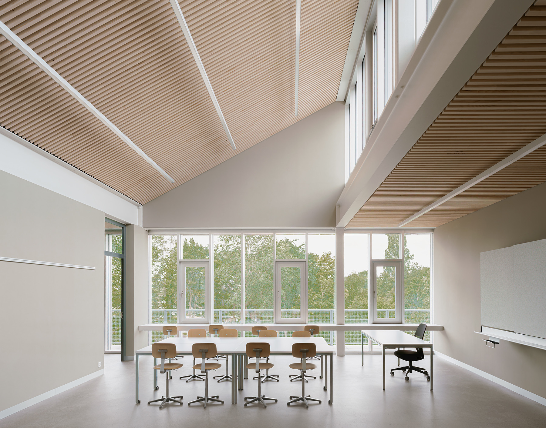 Unterrichtsraum im Schulhaus Zirkusplatz mit Sheddach-Oberlichtern und grossem Fenster zur Umgebung.