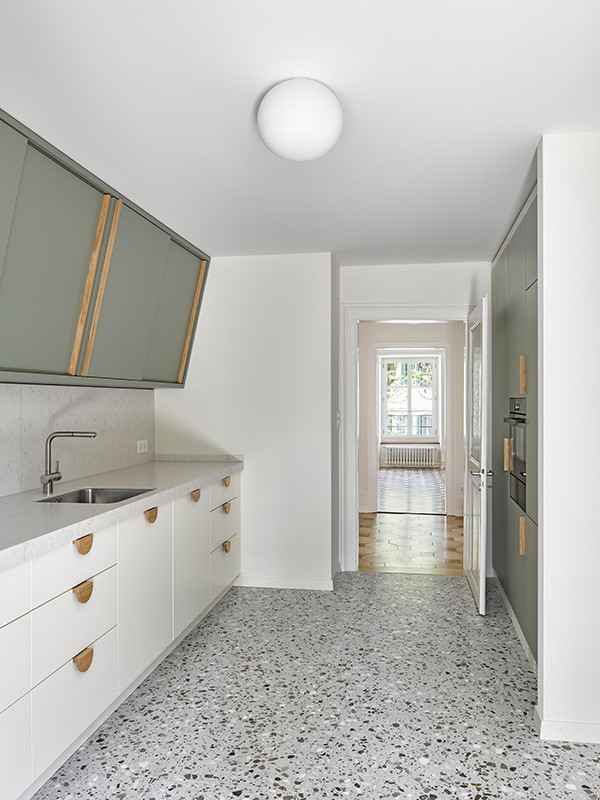 Frisch sanierte Küche mit lindgrünen Oberschränken, Eichengriffen und Terrazzoboden